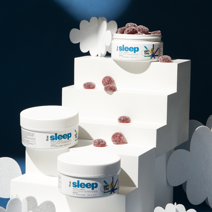 White jars labeled "sleep" with gummies arranged on tiered white platforms against a dark background, surrounded by white cloud cutouts.